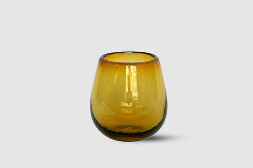 Amber drop-shaped hand-blown tumbler in warm honey tone on white