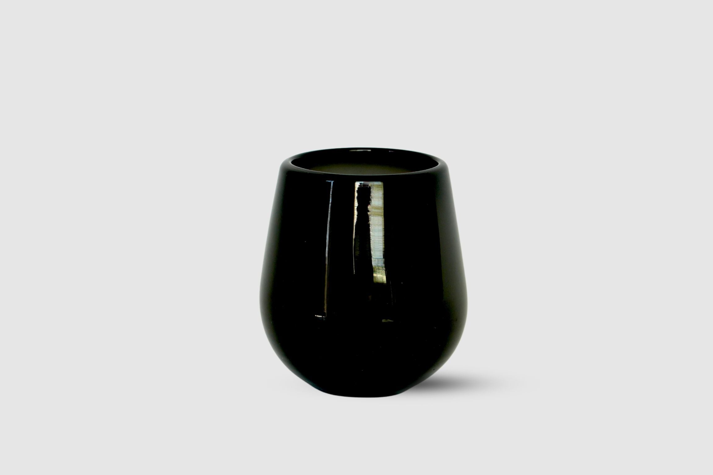 Black drop-shaped hand-blown tumbler with rounded base on white
