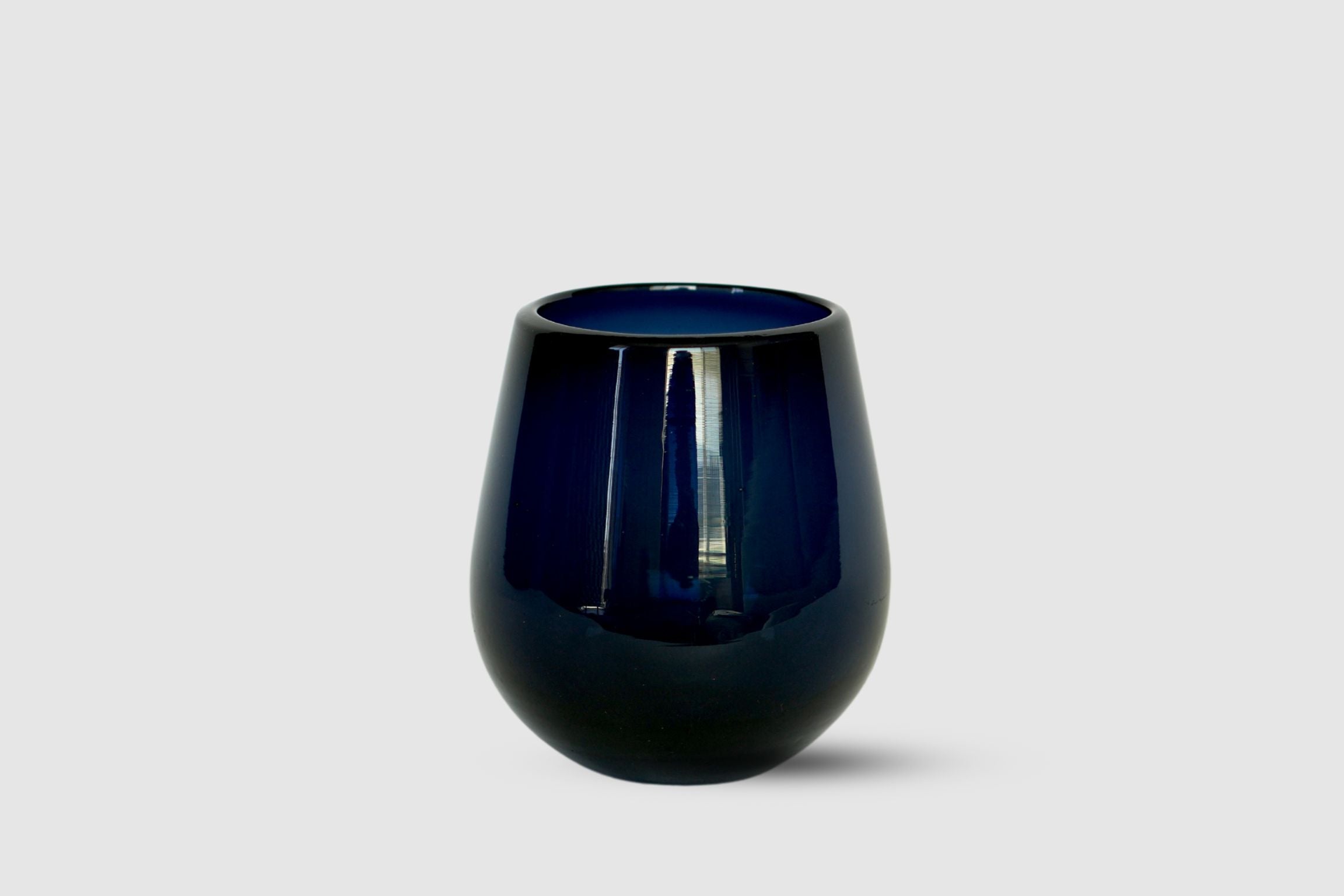 Dark blue drop-shaped hand-blown tumbler photographed on white