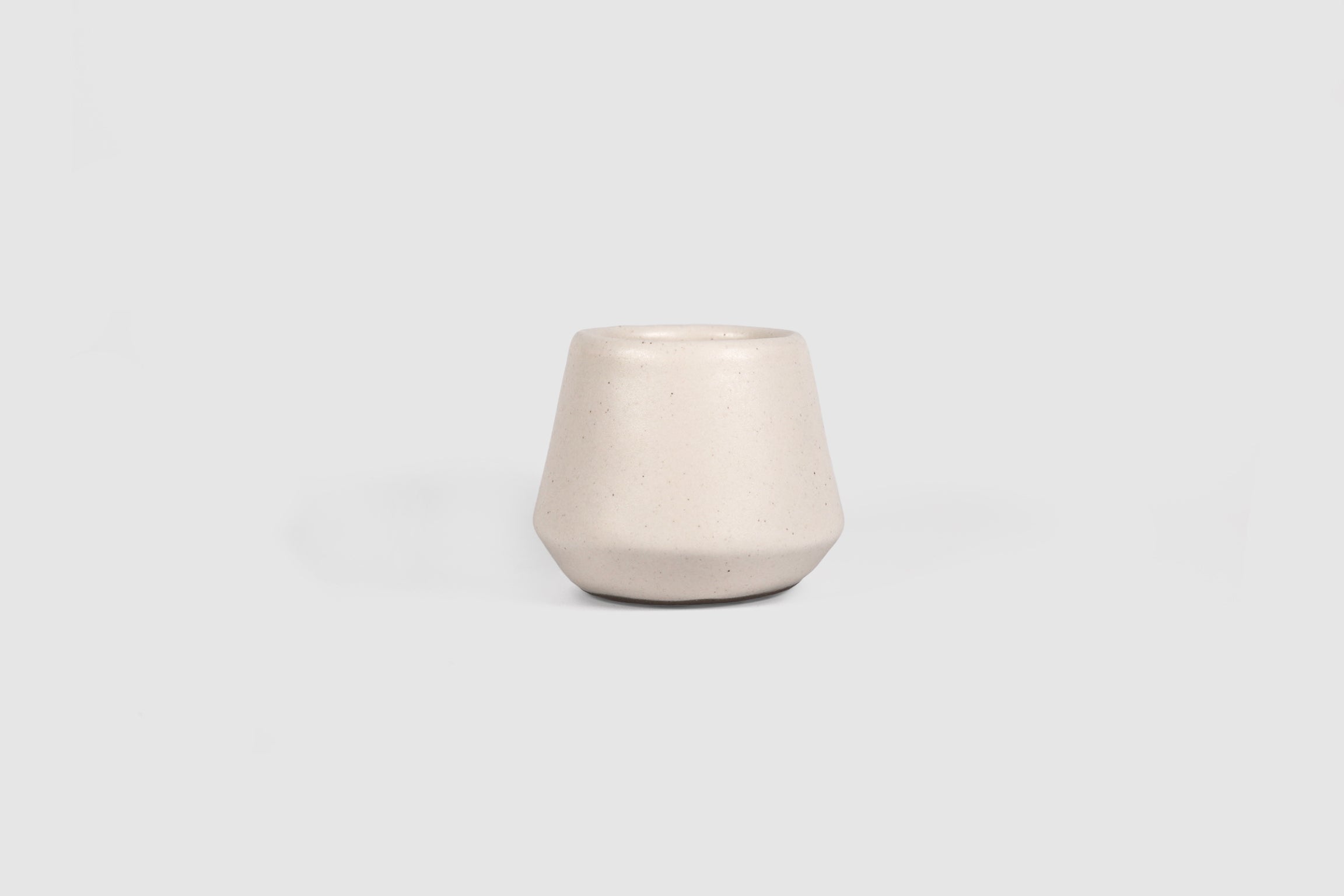 Small ceramic shot vessel with shouldered silhouette.