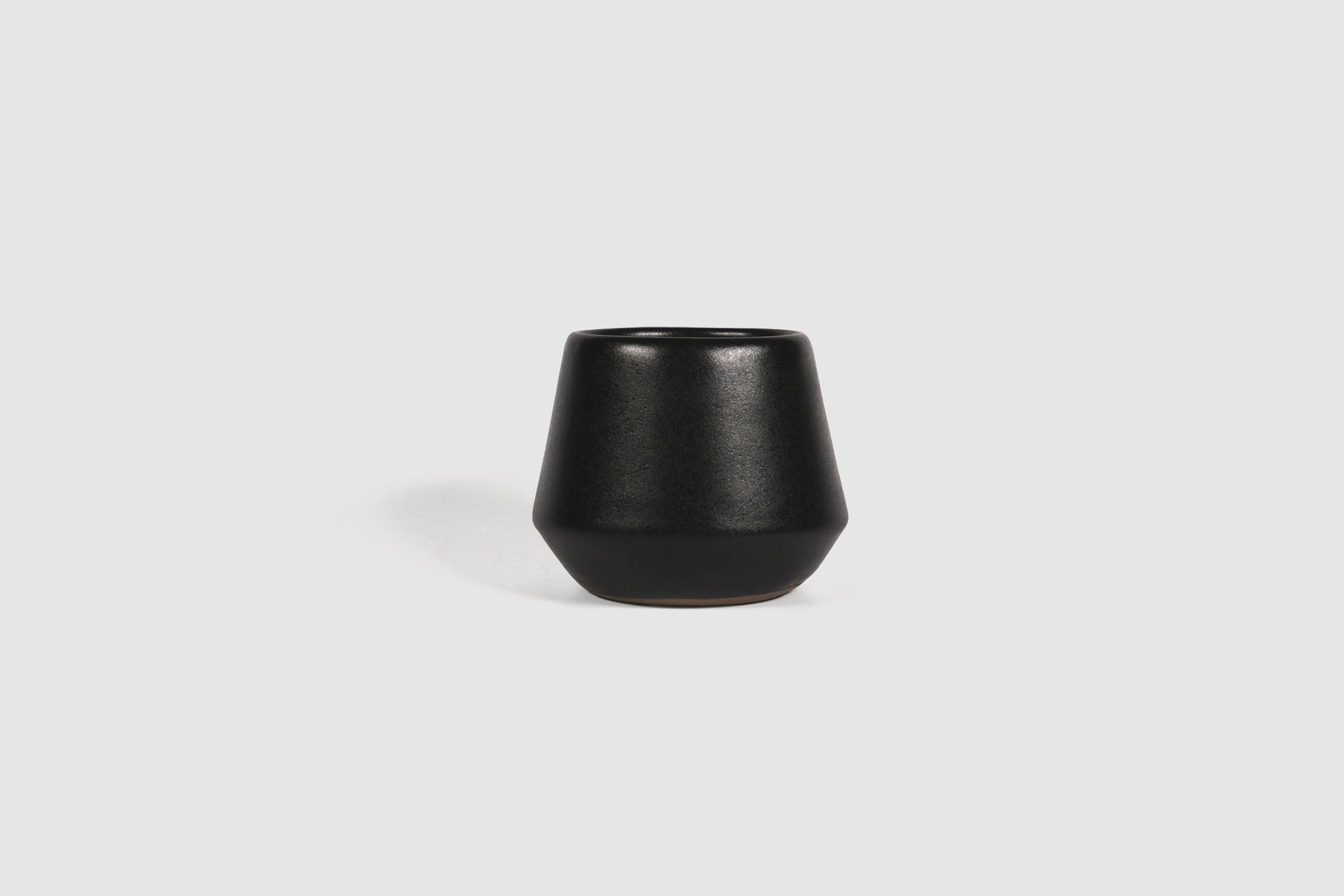 Small ceramic shot vessel with shouldered silhouette.