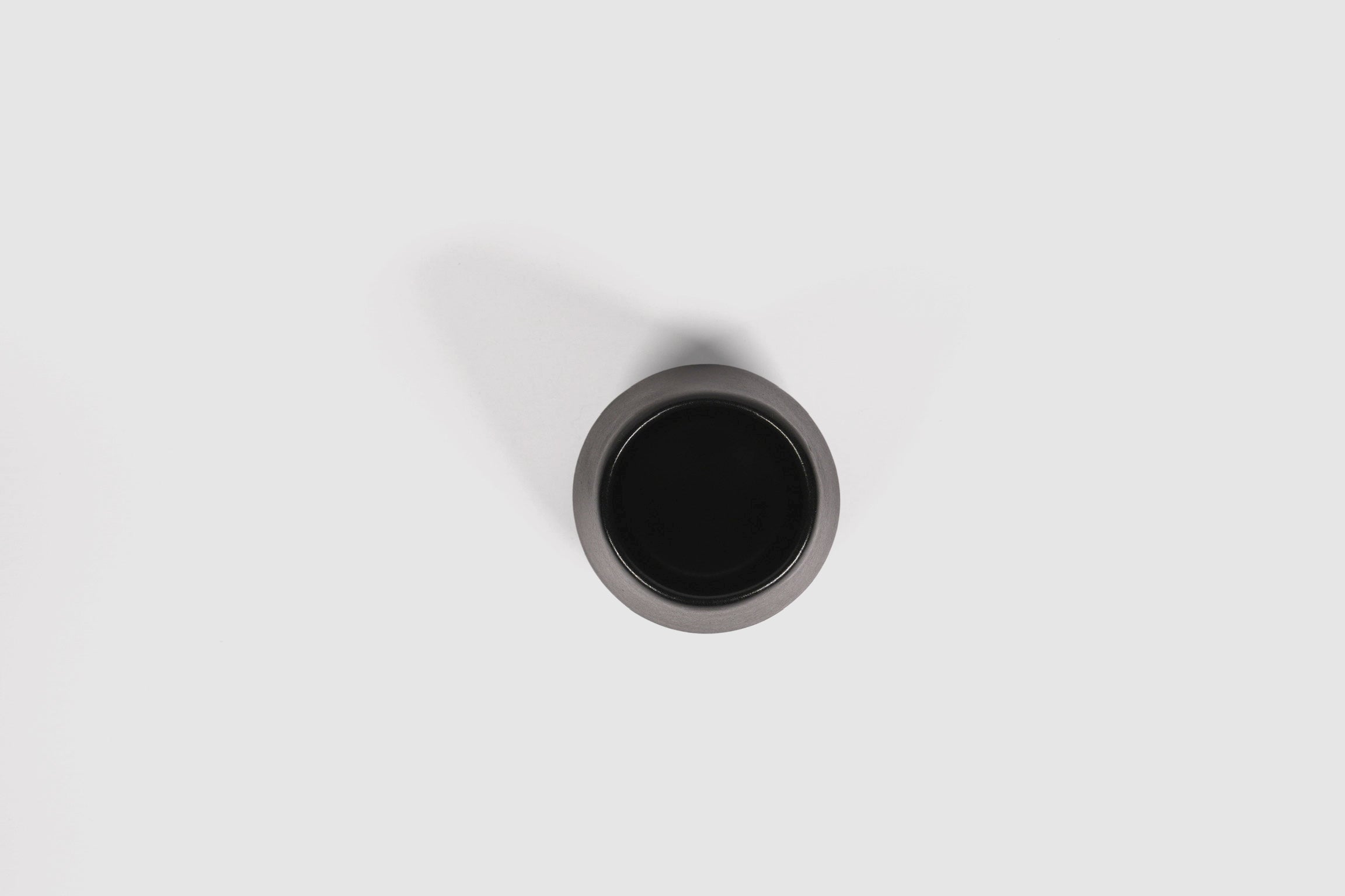 Small ceramic shot vessel with shouldered silhouette.