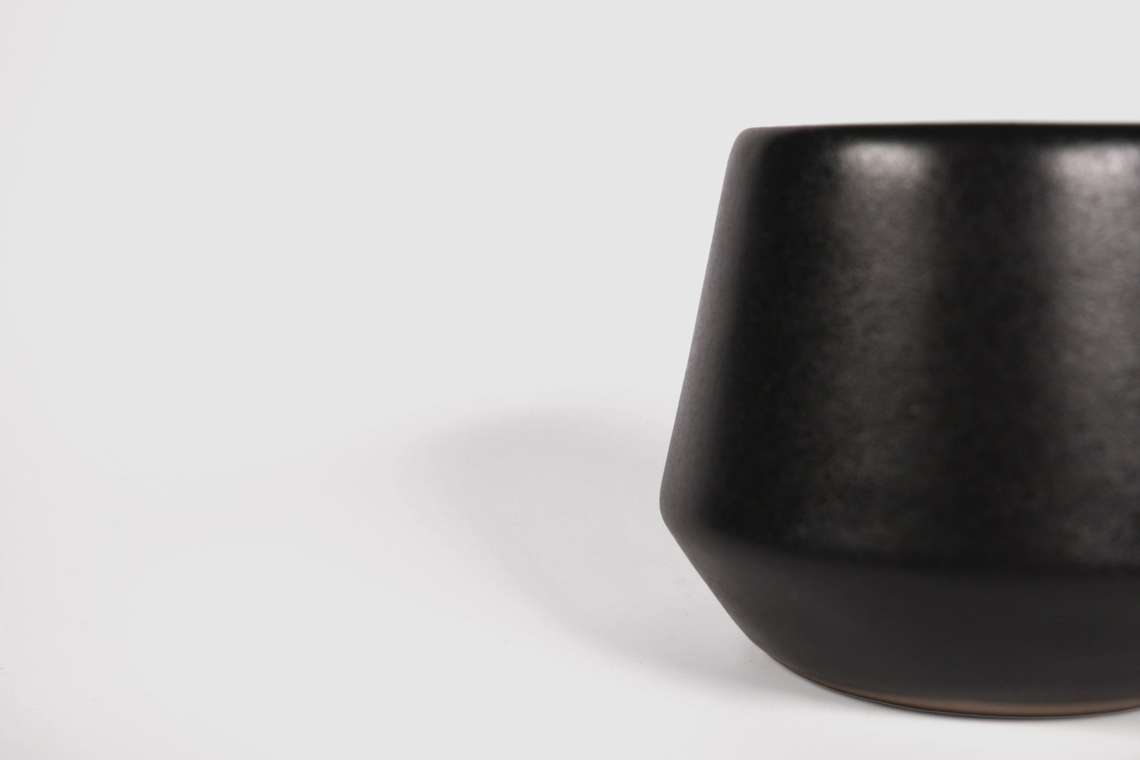 Small ceramic shot vessel with shouldered silhouette.