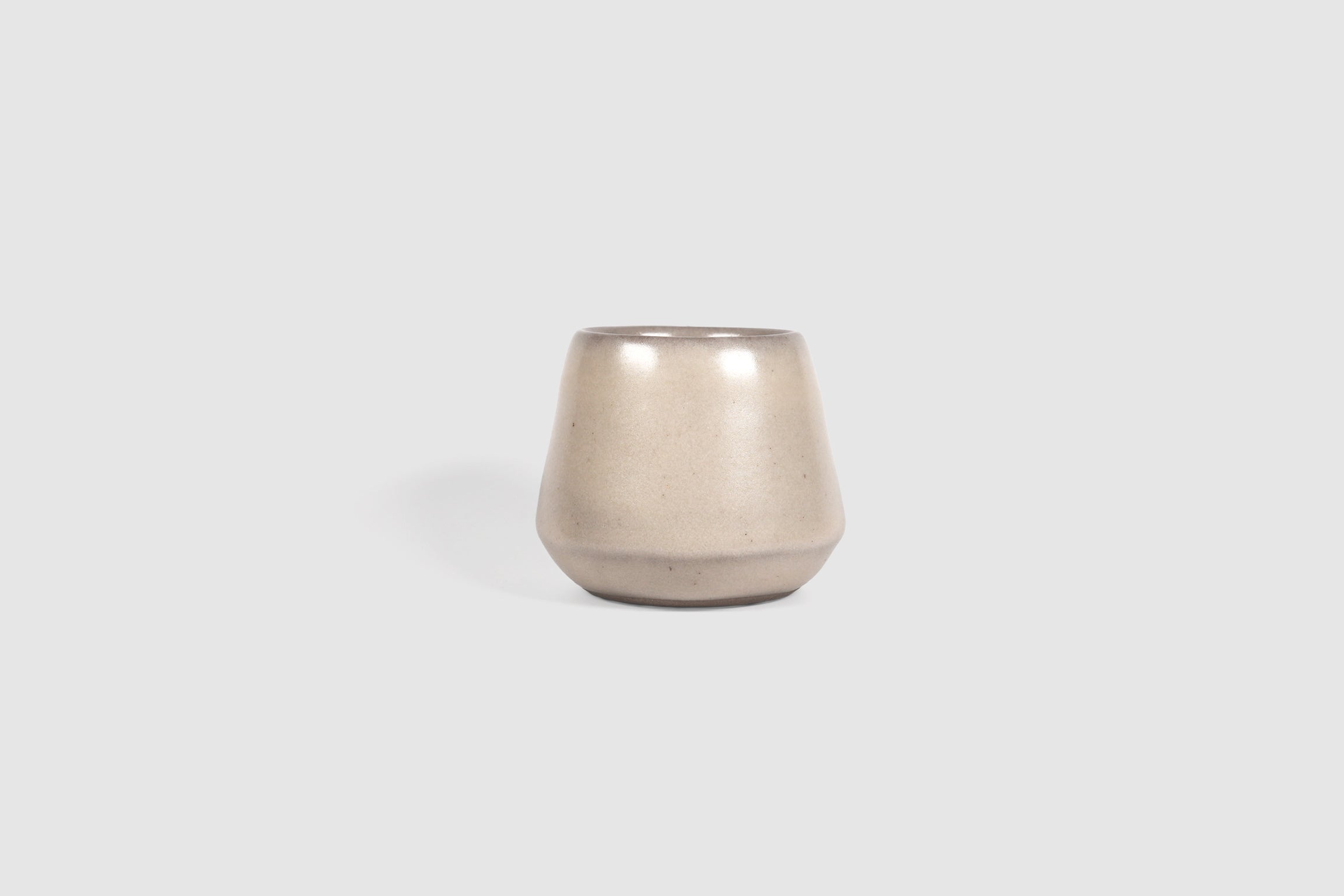 Small ceramic shot vessel with shouldered silhouette.
