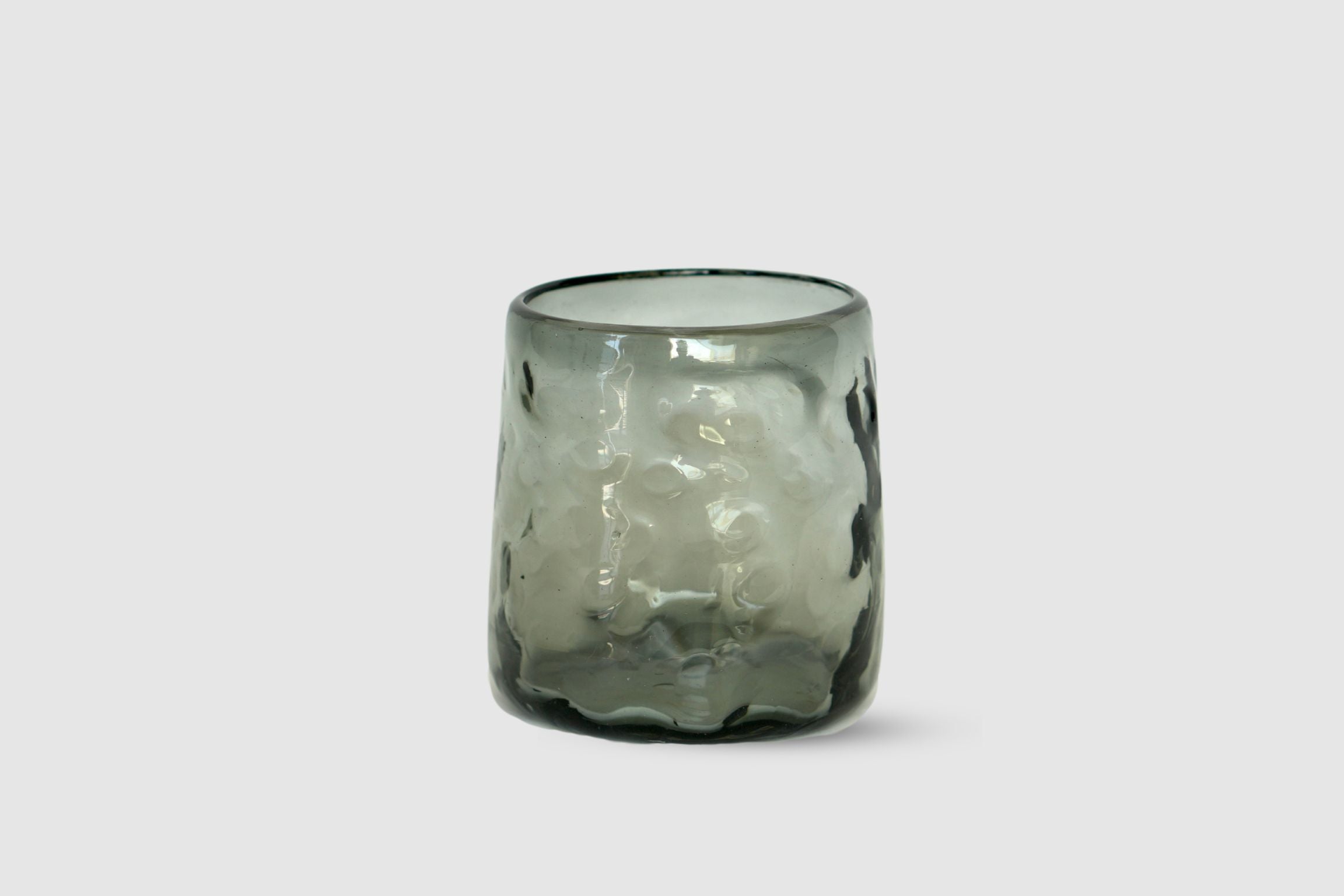 Smoke-tinted hand-blown short highball with irregular silhouette on white