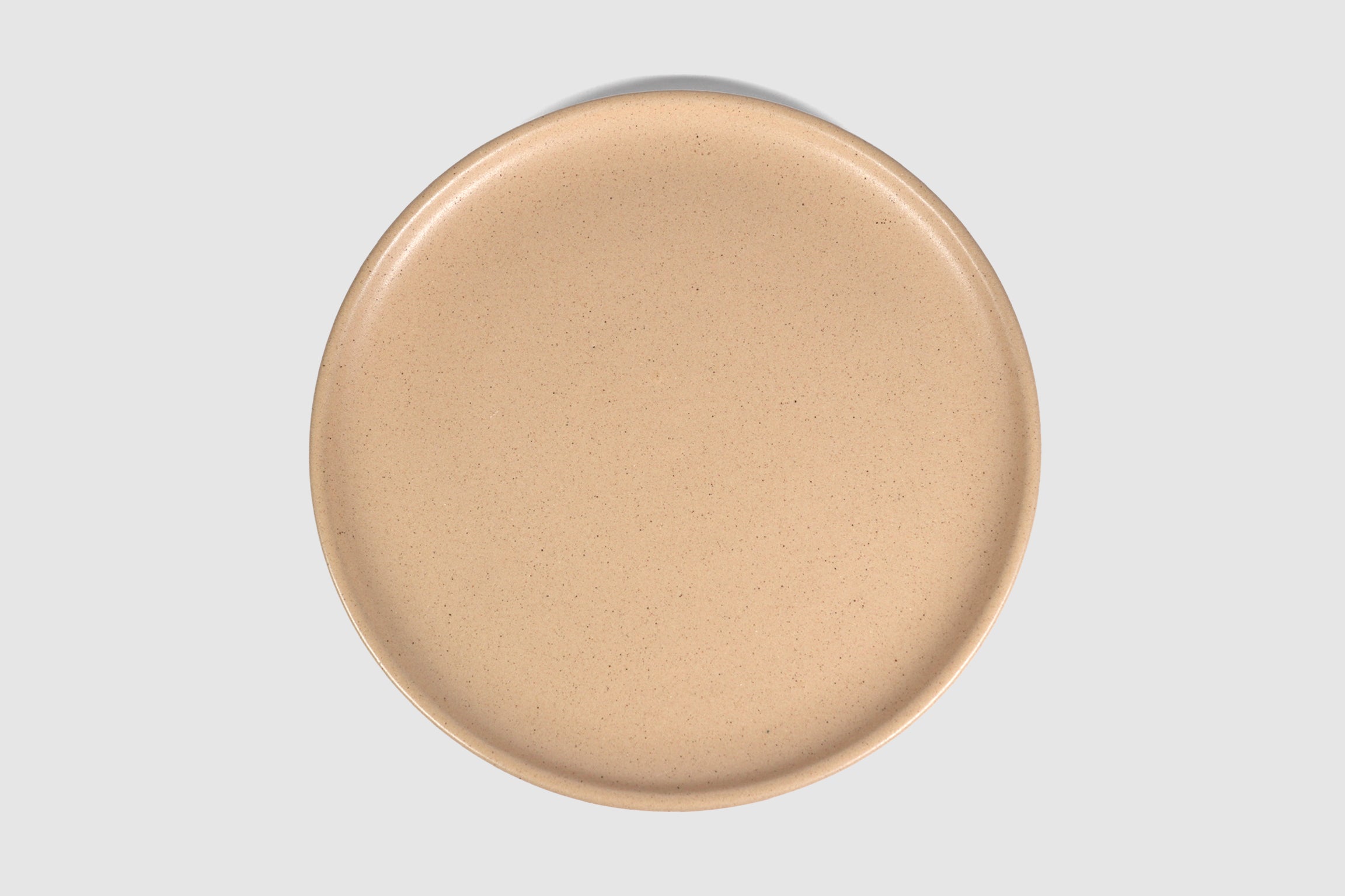 Stacked matte capuchino side plates with low lipped rim on pale ground