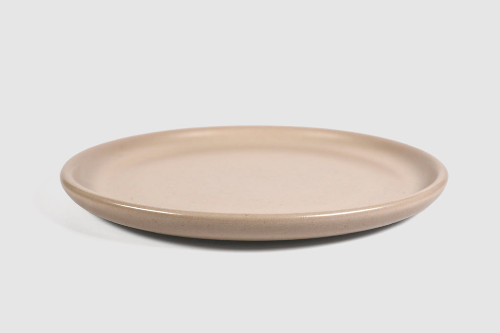 Stacked matte capuchino side plates with low lipped rim on pale ground