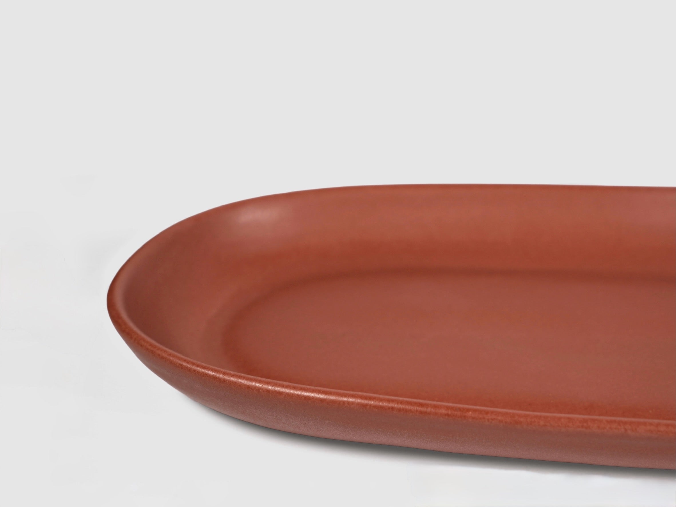 Small Baguette Tray by Humo 1810 – rojizo oval stoneware tray, raised rim, red-clay glaze, 10.25 inch