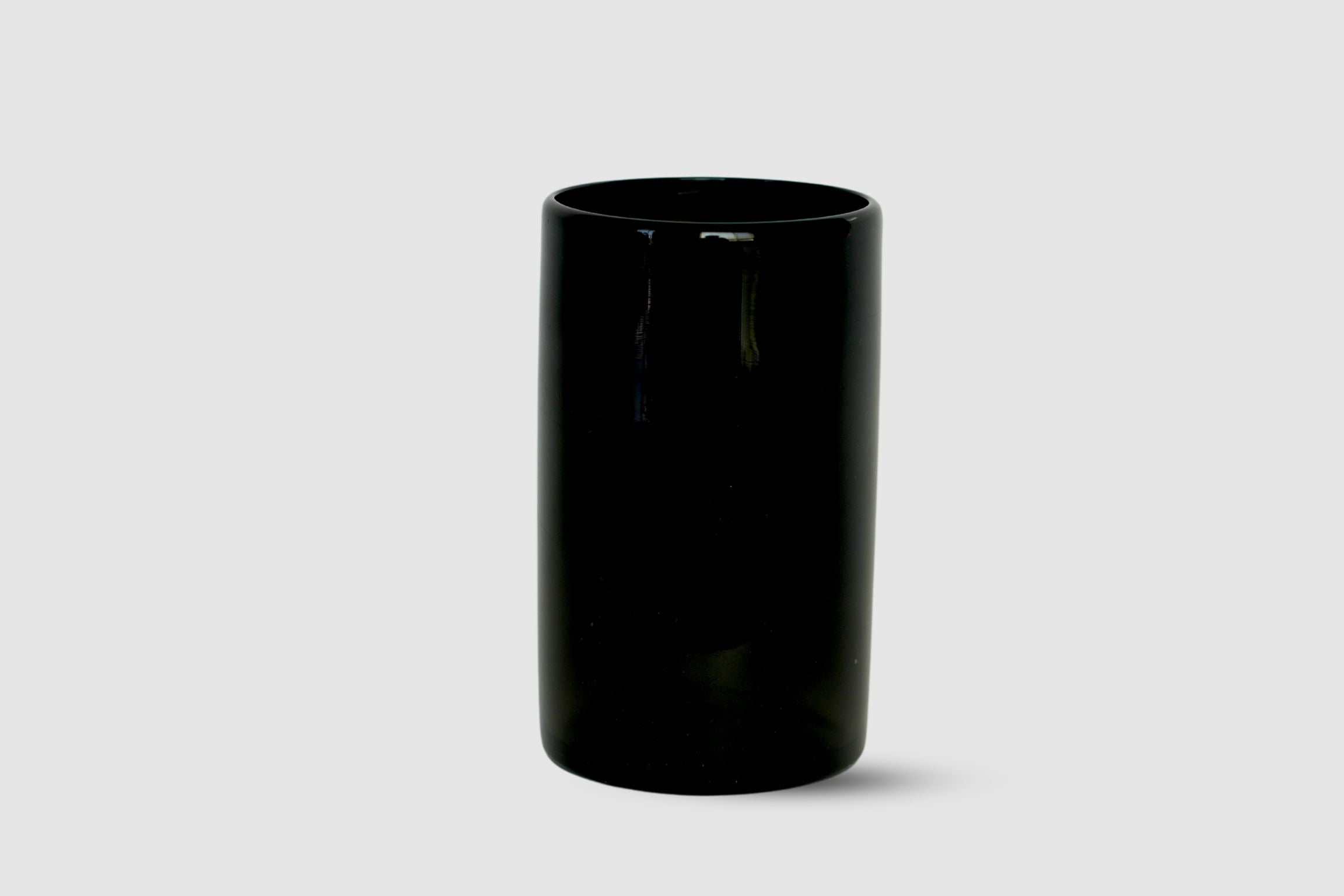 Hand-blown black straight-sided glass tumbler on white background