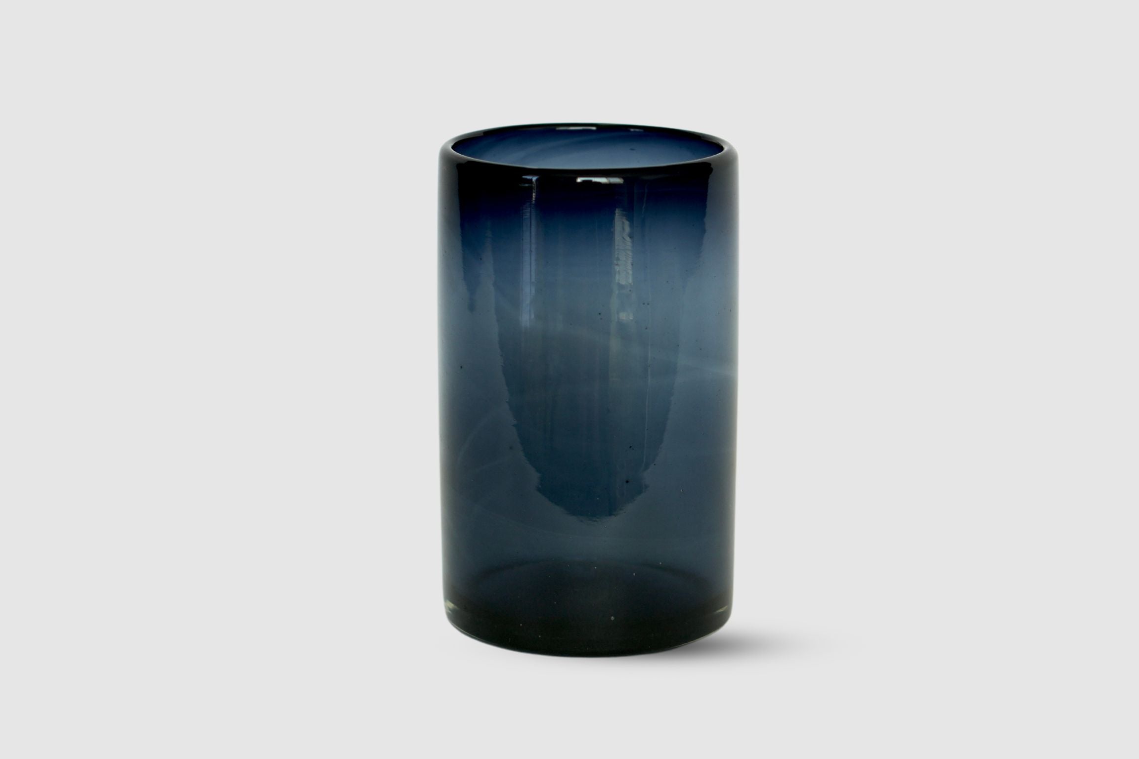 Hand-blown petroleum blue straight-sided tumbler photographed on white