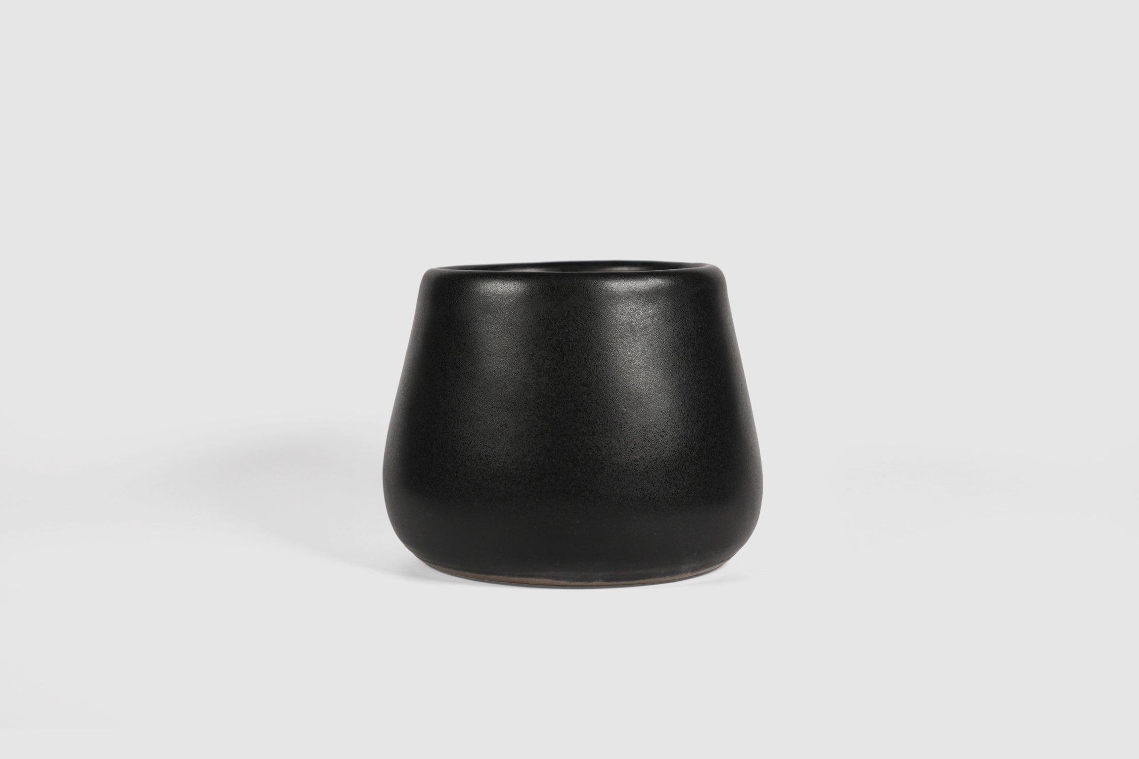 Squat stoneware tumbler, low belly, softly rolled matte rim.